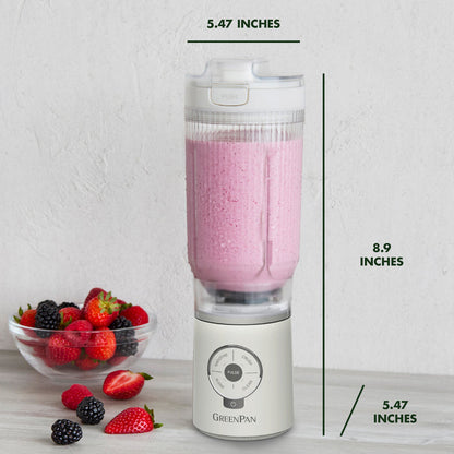 Blender with a pink smoothie and berries on a white surface, with measurements indicated.