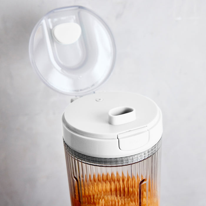 White portable blender with a clear container on a light gray background