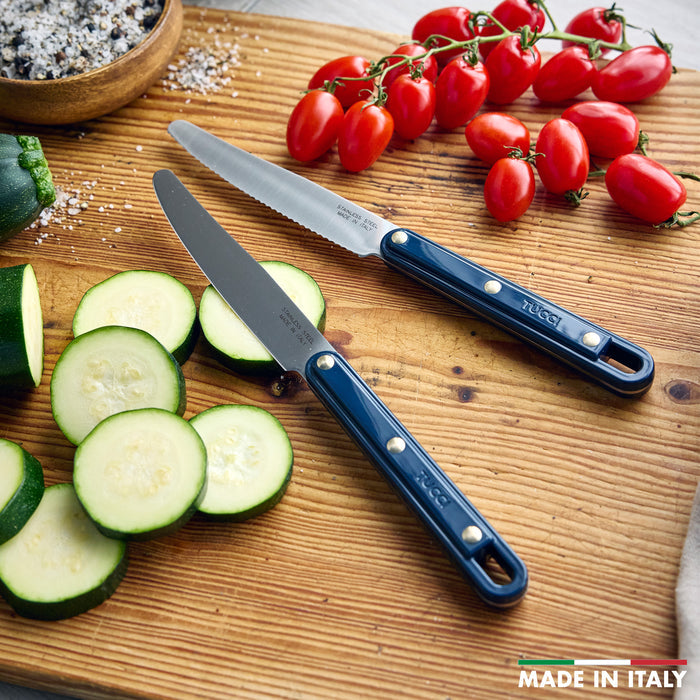 Two knives on a wooden cutting board with sliced zucchini and tomatoes, featuring the brand 'Tucci'