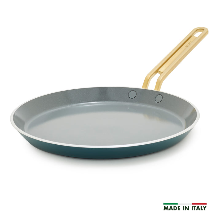 Teal crepe pan with a gold handle on a white background