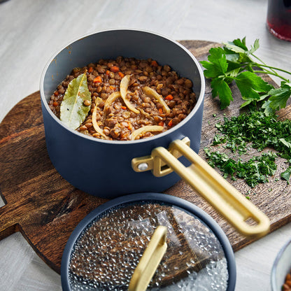 Lentil stew in a white ceramic pot on a wooden board with parsley, part of a 3-piece mini cookware set.