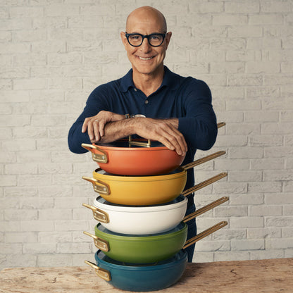 Five Venetian Teal Stanley Tucci 4.5-quart pans arranged on a table with a smiling man standing behind them.