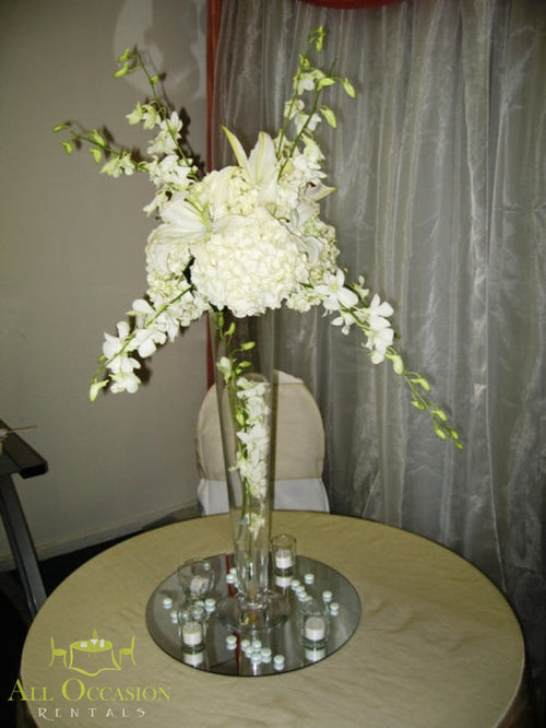 Tall White Floral Centerpiece Rental featuring elegant white flowers in a glass vase on a table.