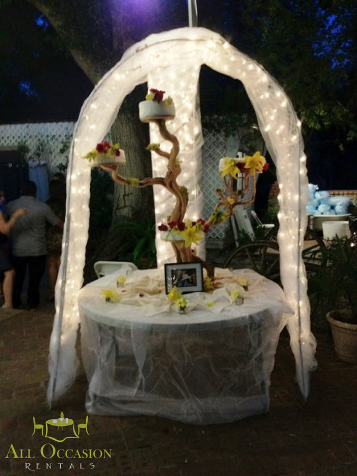 Tree wedding cake stand adorned with lights and flowers, perfect for receptions from Corona event rentals.