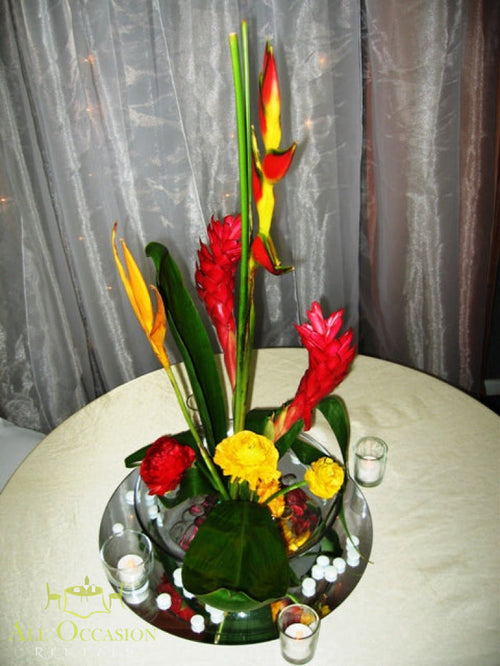 Tropical Floral Centerpiece Rental featuring red ginger, heliconia blooms, and vibrant yellow accents on a table.
