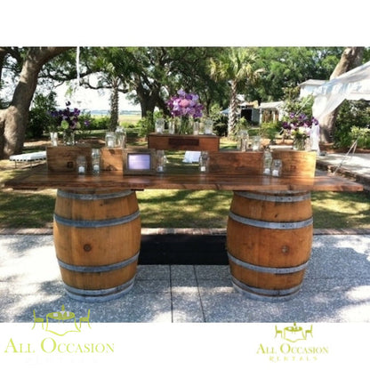 Beautiful wine barrel bar or table set up outdoors with floral arrangements.